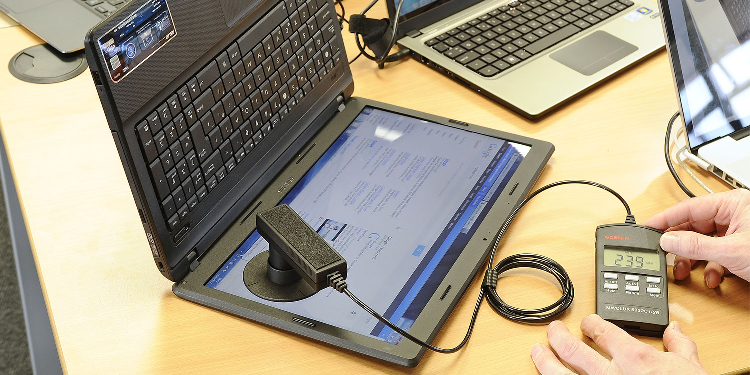 A laptop's screen being tested with a scientific instrument