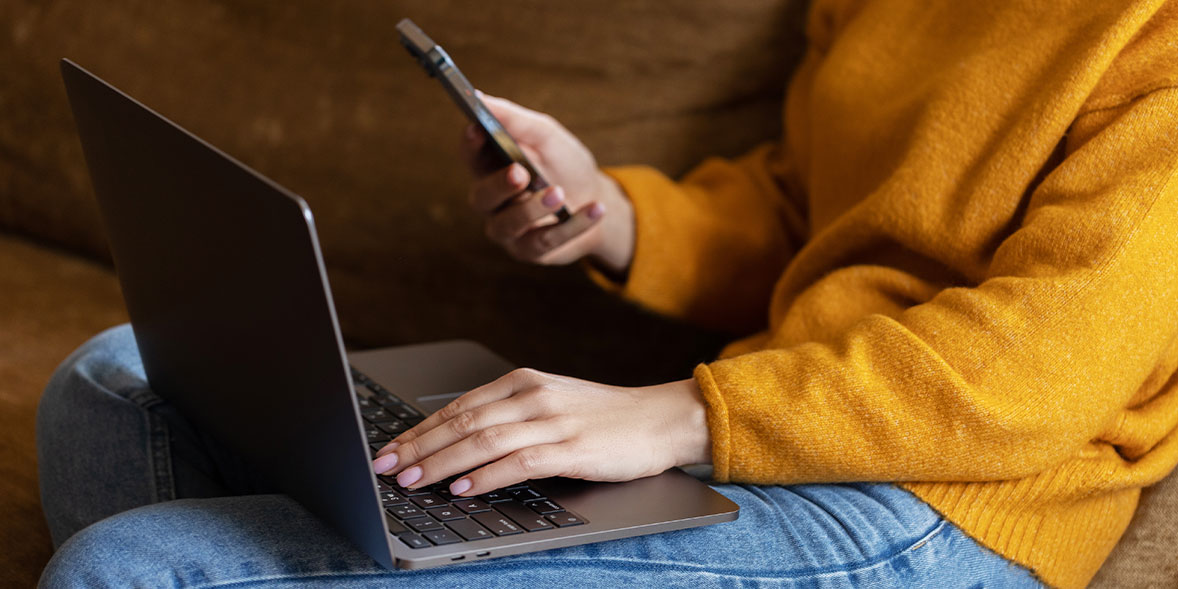 Person using an iPhone and a MacBook laptop