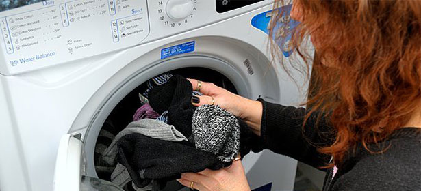 Woman carrying clothes to a tumble dryer